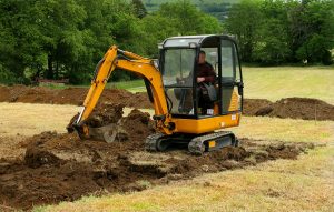 A man operating a mini digger in a field.